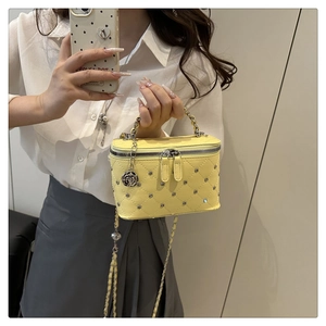 Detail of yellow mini rhinestone box bag with silver rose charm and chain strap