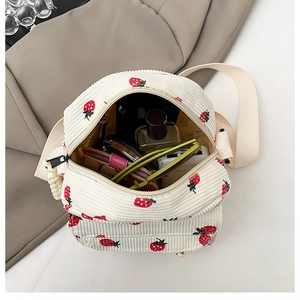 Detail of white corduroy strawberry crossbody bag showing interior storage capacity