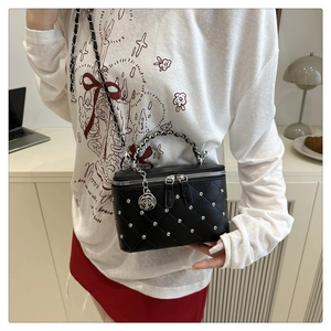 Detail of black quilted crossbody bag with silver studs and rose charm chain strap