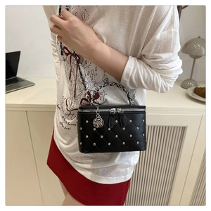 Detail of black quilted mini box bag with silver studs and a rose charm pendant