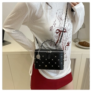 Detail of black quilted vanity bag with silver studs and rose pendant accessory