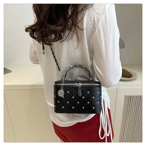 Quilted black crossbody box bag with silver studs and rose charm shown on model