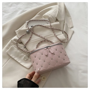 Detail of pink quilted box bag with silver camellia charm and leather chain strap