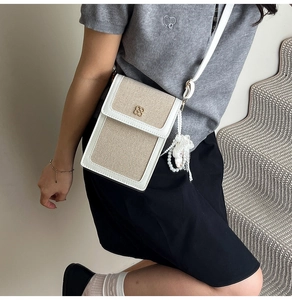 Detail of canvas crossbody bag with clover buckle and cartoon character pearl charm