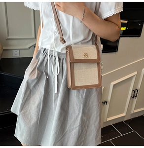 Detail of canvas crossbody bag with brown leather trim and clover metal buckle