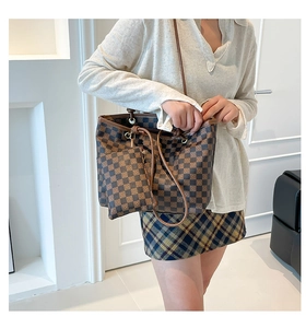 Detail of checkered pattern tote bag with matching pouch and brown leather handles