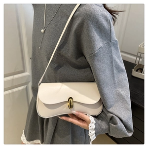 Close-up of minimalist beige shoulder bag with gold U-shaped lock on a model