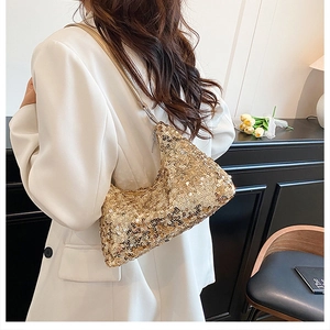 Détail d'un sac hobo à paillettes dorées porté avec un blazer blanc élégant
