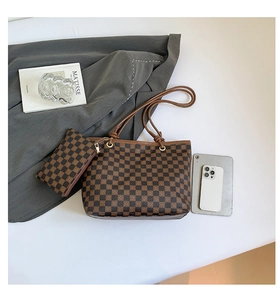 Dettaglio del set borsa shopper a scacchi con pochette coordinata su sfondo neutro