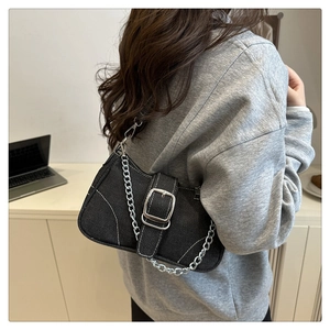 Close-up of black denim baguette bag with silver buckle and white contrast stitching