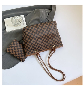 Dettaglio della borsa shopper a scacchi con pochette coordinata su superficie bianca