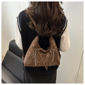 Détail macro du sac bandoulière marron foncé avec fermetures éclair et nœuds élégants