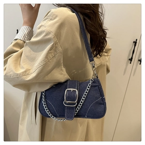 Detail of denim baguette bag with silver buckle and chain on model in trench coat