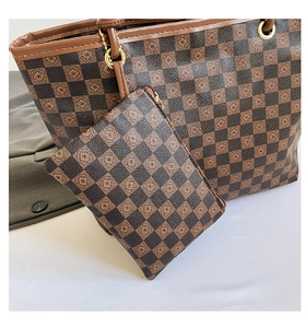 Dettaglio della borsa shopper a scacchi e pochette con motivi floreali e manici marroni