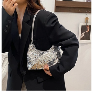 Détail du sac demi-lune à paillettes avec bandoulière argentée sur un blazer noir