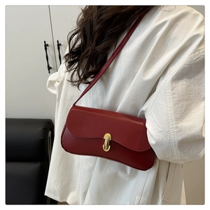Detail of red vintage baguette bag with smooth leather and a gold oval metal buckle