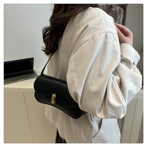 Detail of classic black underarm bag with gold oval twist lock and slim shoulder strap
