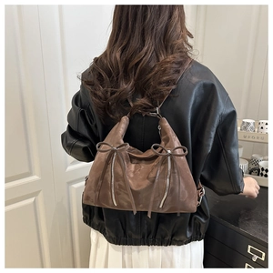 Vue arrière d'un sac à main en daim marron avec nœuds décoratifs sur un mannequin