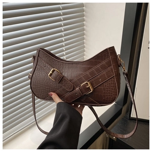 Detail of dark brown crocodile texture underarm bag with gold buckles and straps