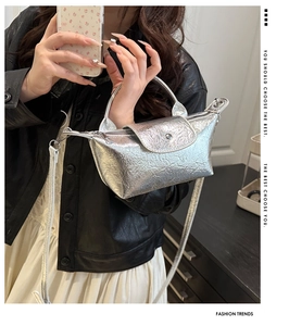 Detailed view of silver metallic dumpling bag with wrinkled texture and pearl accents
