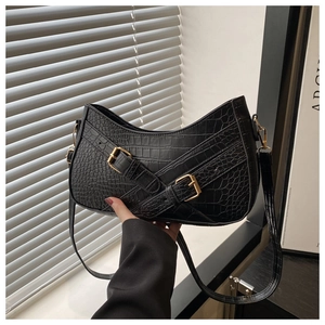 Detail of black crocodile texture shoulder bag with gold metal buckle and cross straps