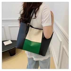 Detailed side view of a large color-block leather tote bag on model in a minimalist setting