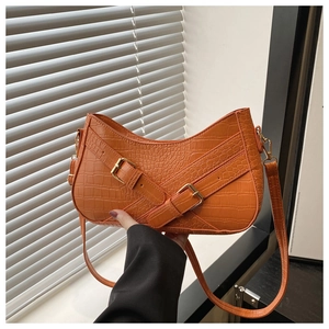 Detailed view of orange crocodile pattern faux leather handbag with golden metal buckles