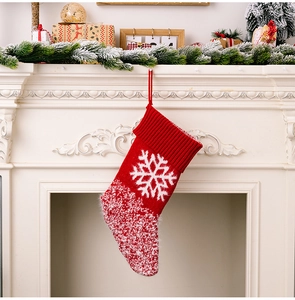 Detail of red knitted Christmas stocking with white snowflake pattern on a fireplace