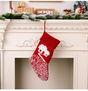 Detail of red knit Christmas stocking with white snowflake house pattern on a mantel