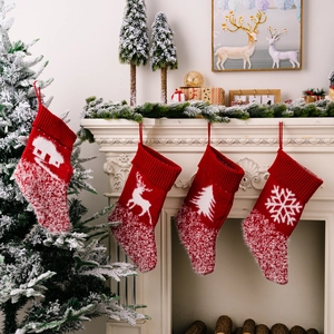 Set mit vier roten Strick-Nikolausstiefeln mit Rentier und Schneeflocke am Kamin aufgehängt