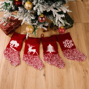 4er-Set rote Strick-Weihnachtssocken mit weißen festlichen Motiven auf Holzboden