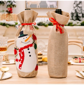 Detail of burlap wine bags with snowman embroidery and festive red ribbon drawstring