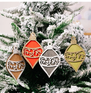 Detail of glitter wooden teardrop Christmas ornaments hanging on snowy pine branches