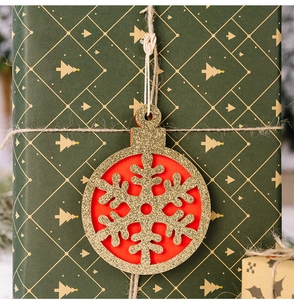 Close-up of circular snowflake wooden pendant with gold glitter and red backing