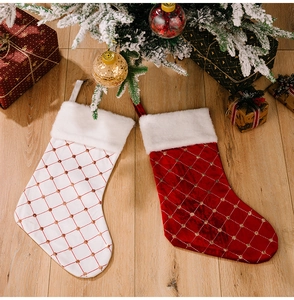Close-up of red and white quilted Christmas stockings with gold embroidery on wooden floor