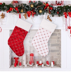 Detail of red and white quilted satin Christmas stockings with gold beads on mantel