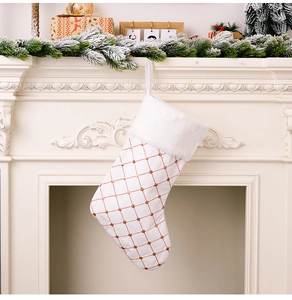 Detail of white Christmas stocking with gold sequins hanging on a white fireplace