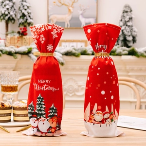 Close-up of red Christmas wine bottle covers with snowflakes and gold ribbon ties