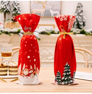 Close-up of red Christmas wine bottle bags with golden ribbons and Merry Christmas prints