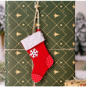 Mini-Weihnachtssocke in Rot mit Schneeflocke und Punkten auf einer Geschenkbox hängend