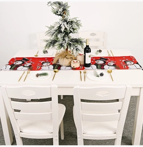 Weihnachtlicher Strick-Tischläufer mit Schneemann auf weißem Tisch mit festlicher Dekoration