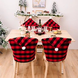 Detail of red and black buffalo plaid Christmas chair covers with white plush pom-poms