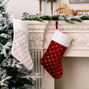 Luxurious red and white velvet Christmas stockings with gold diamond embroidery hanging on a fireplace