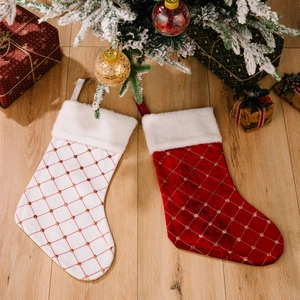 Red and white quilted Christmas stockings with plush trim on light wooden background