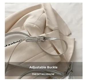 Detail of adjustable silver buckle and metallic textured strap on a silver hobo bag