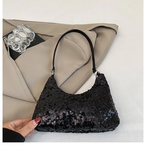 Vue détaillée d'un sac à bandoulière en paillettes noires avec sangle en cuir sur un blazer