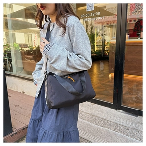 Waterproof black nylon crossbody bag with bright orange zipper detail on street model