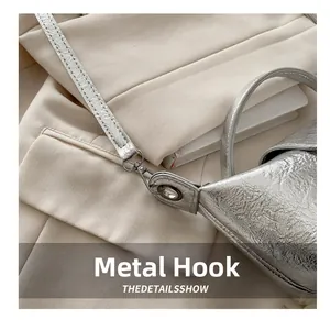Detail shot of silver metallic crossbody dumpling bag showing durable metal hook hardware