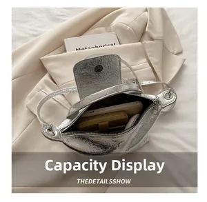 Silver metallic dumpling bag showing large capacity with phone and wallet inside