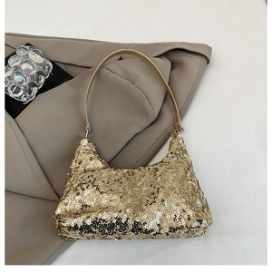Détail d'un sac à épaule à paillettes dorées avec bandoulière sur un blazer chic